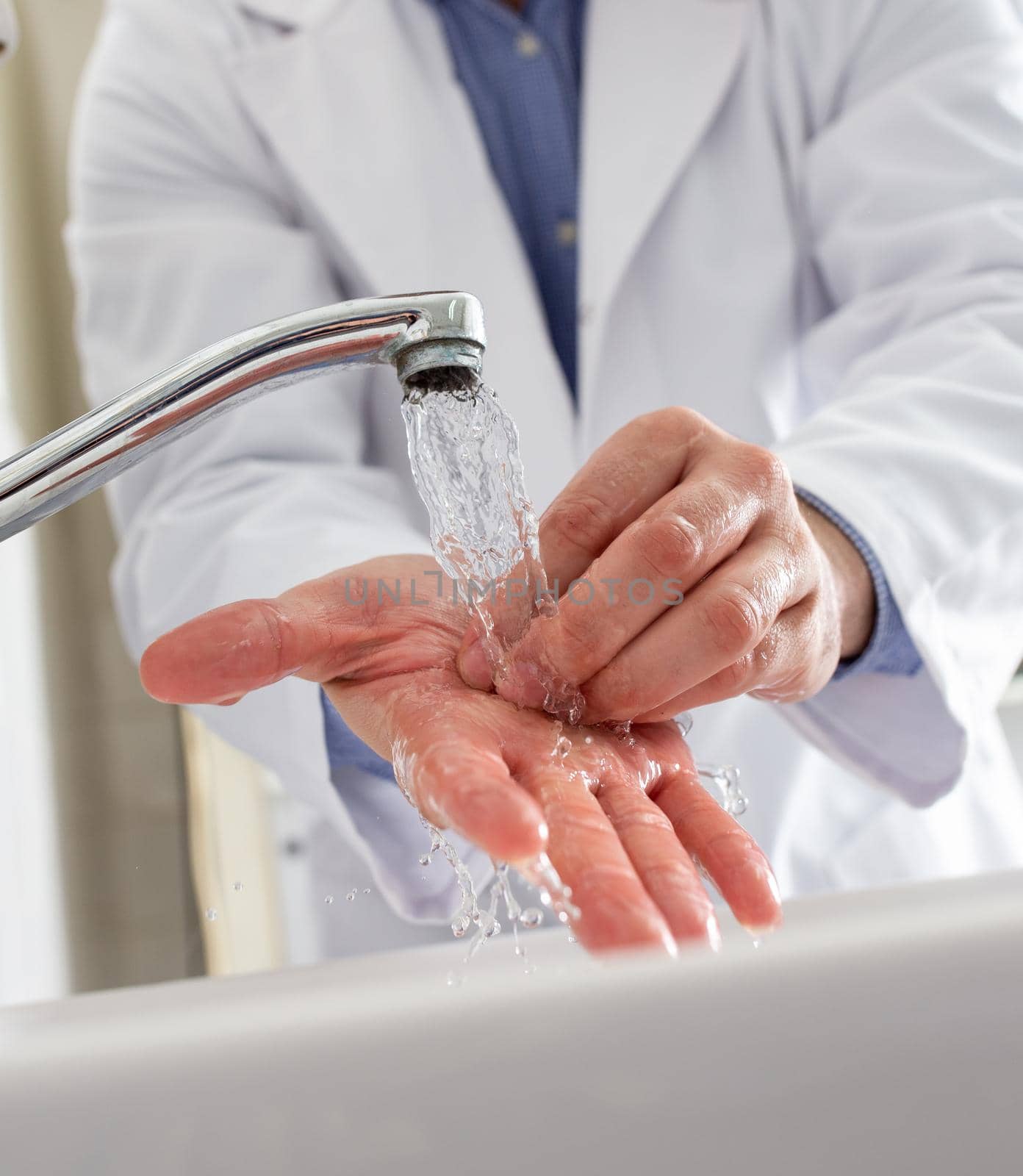 Close up of doctor's hands washing on tap water in sink before working in hospital