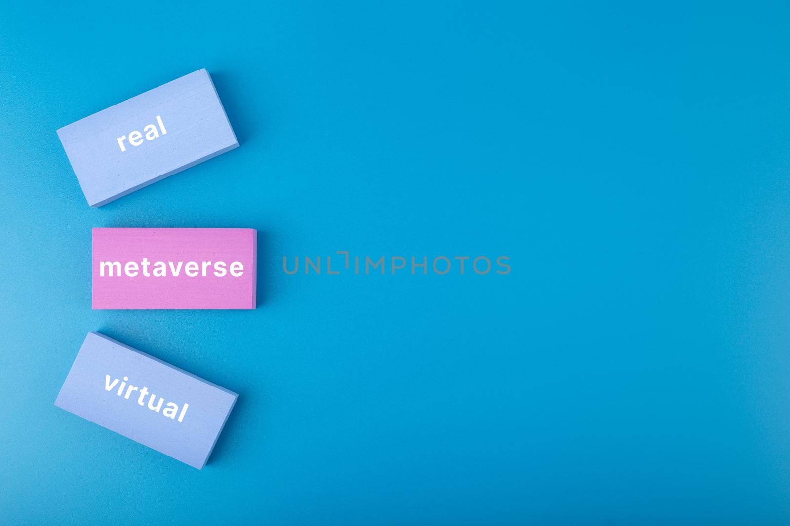 Metaverse modern minimal concept in blue colors with copy space. Written metaverse, real, virtual words on blue and pink rectangles against blue background. Future technologies.