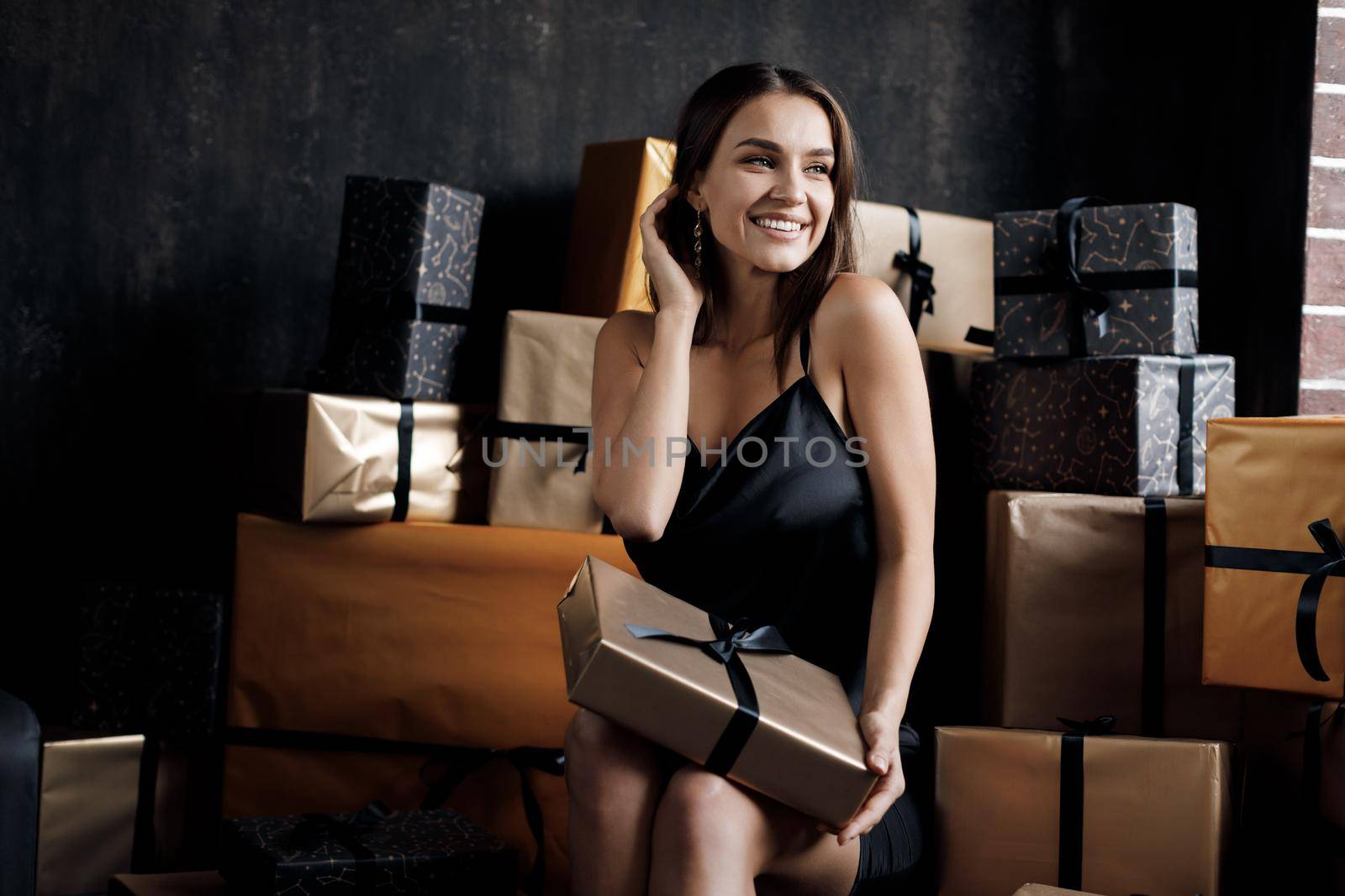 Young happy laughing woman in black dress with gift. High quality photo