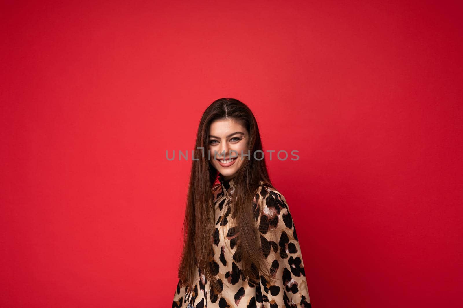 Photo of young happy smiling beautiful fashionable sexy brunette woman wearing stylish leopard blouse isolated on red background with empty space. Positive concept.