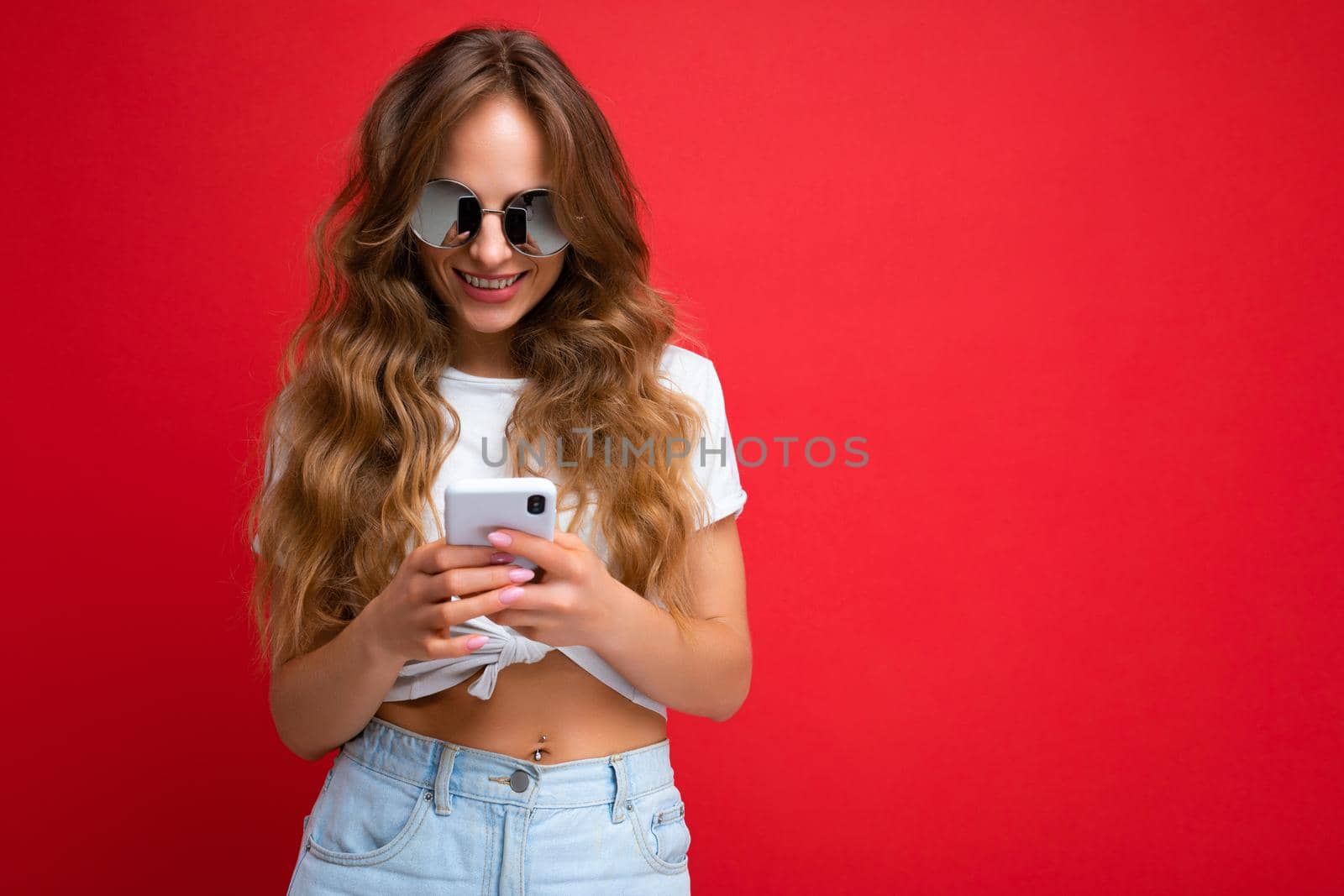 Beautiful young woman wearing casual clothes standing isolated over background surfing on the internet via phone looking at mobile screen.