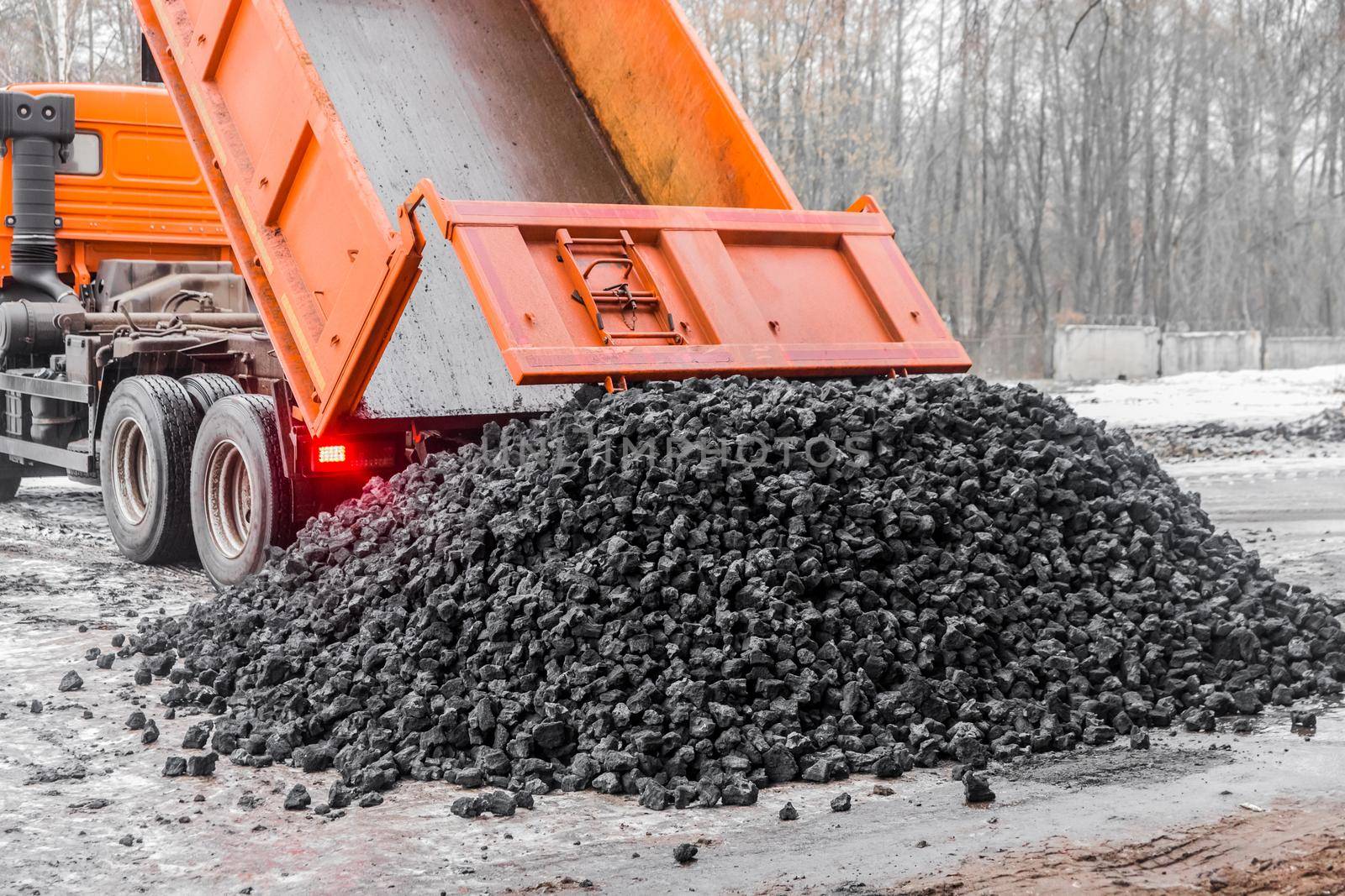 Dump truck in the industrial zone unloads coking coal from the body.