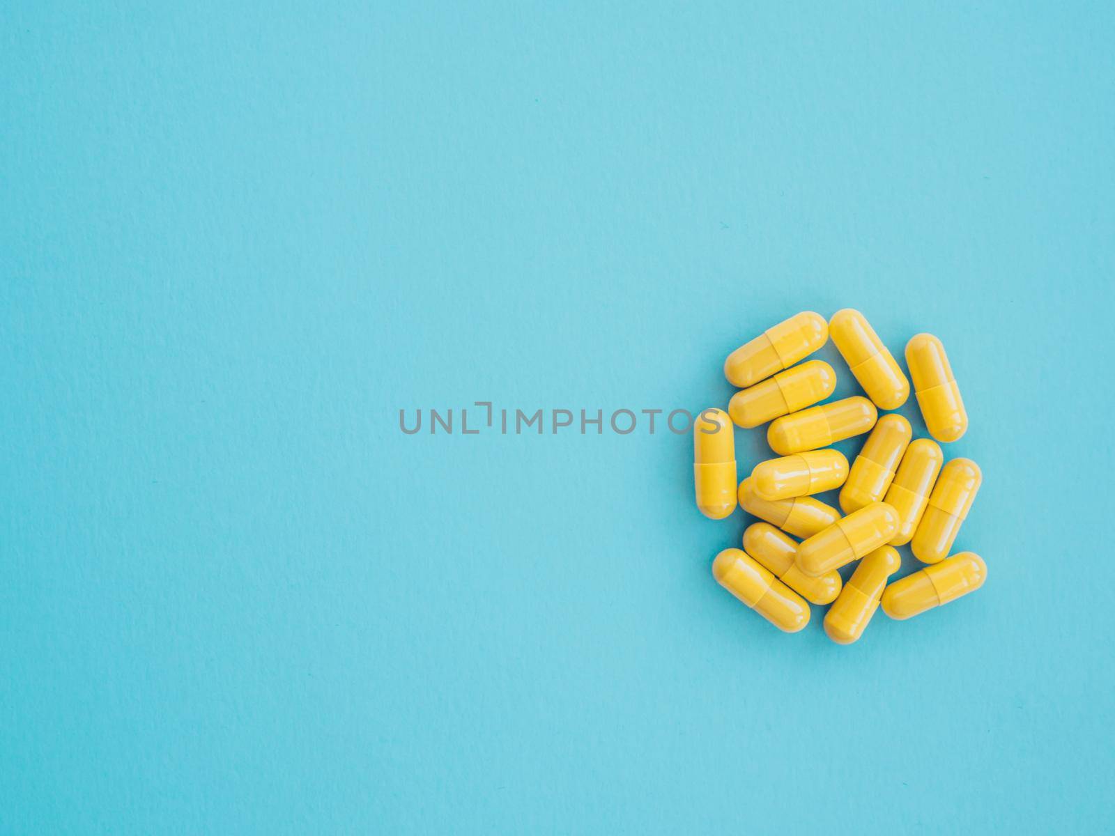 Concept of healthcare and medicine. treatment of viruses. Assortment of yellow medicinal pharmaceutical products, tablets, pills, capsules on blue background. Space for text.