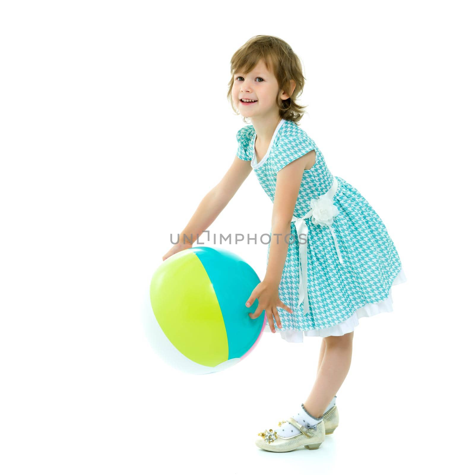 A good girl is playing with a big inflatable ball. The concept of a happy childhood, recreation in nature, exercise. Isolated on white background.