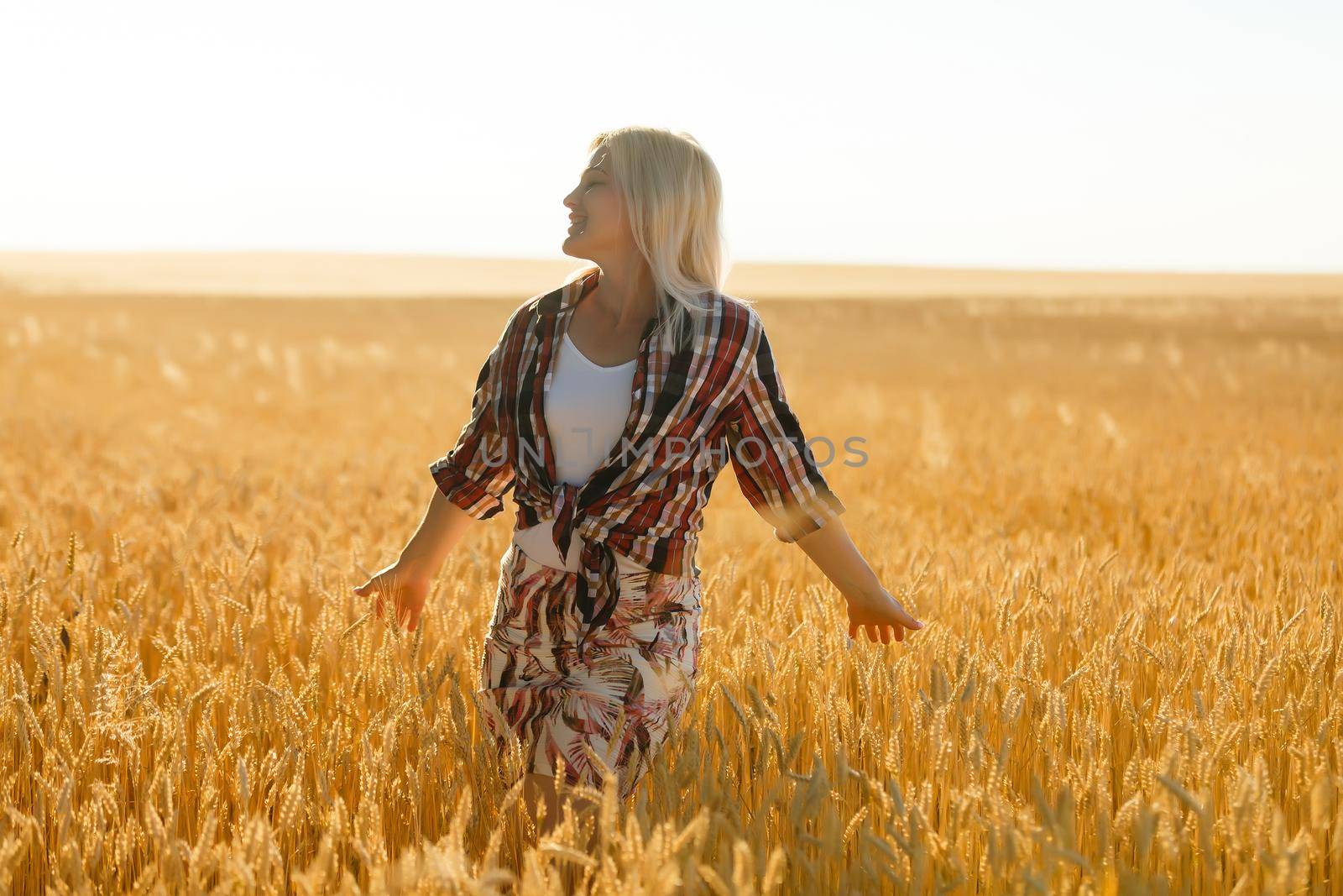 A girl in the midst of wheat spikelets. Caucasian woman posing with spikelets outside. by Andelov13