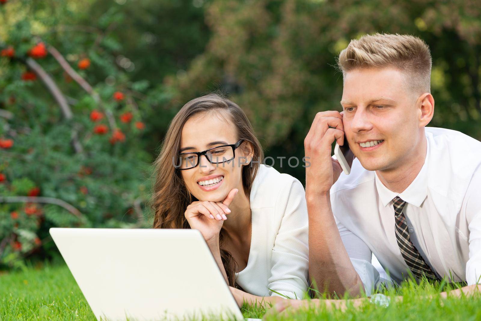 businessman and businesswoman with a laptop in a city park by adam121
