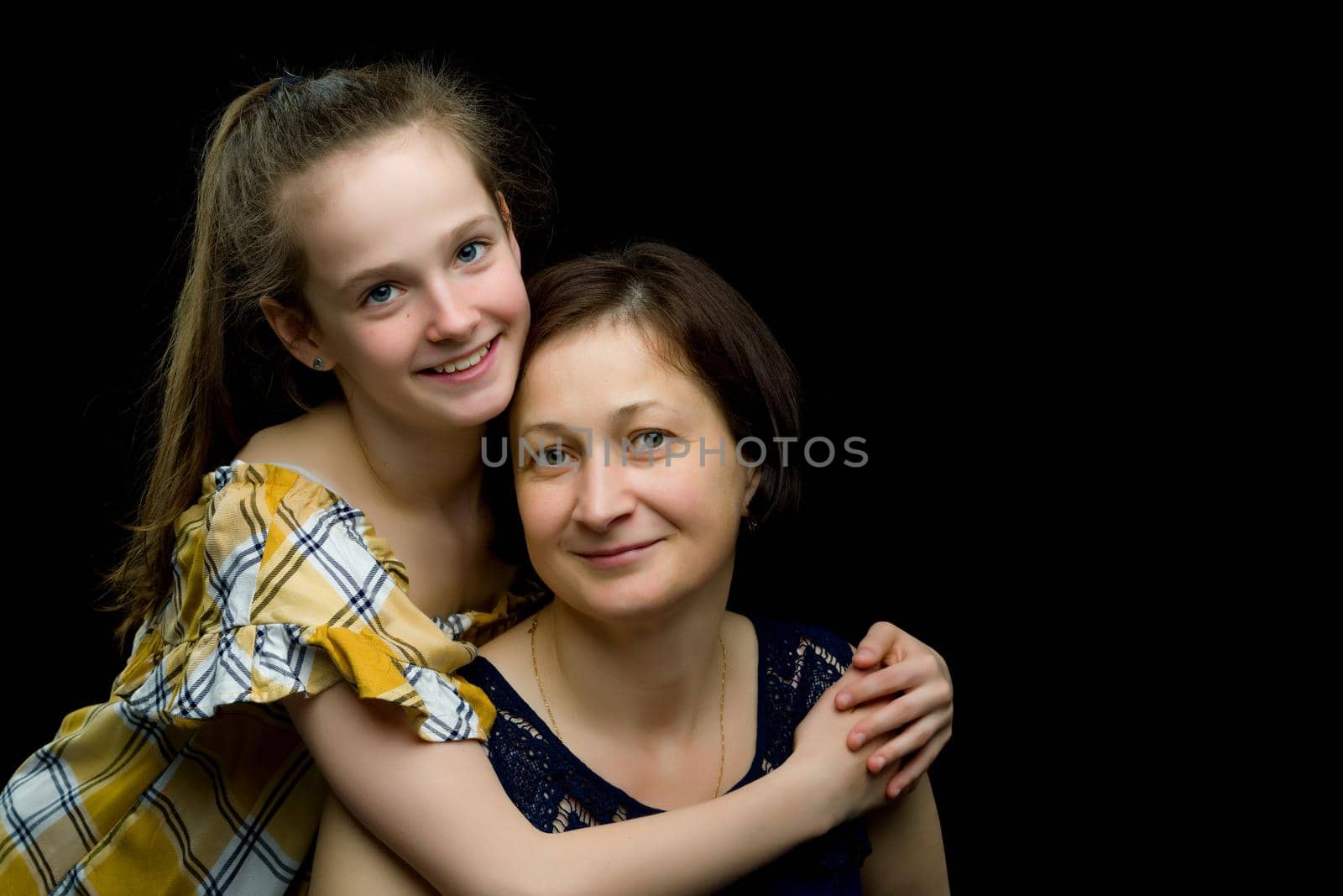 Happy family mom and little daughter, studio portrait.On black background