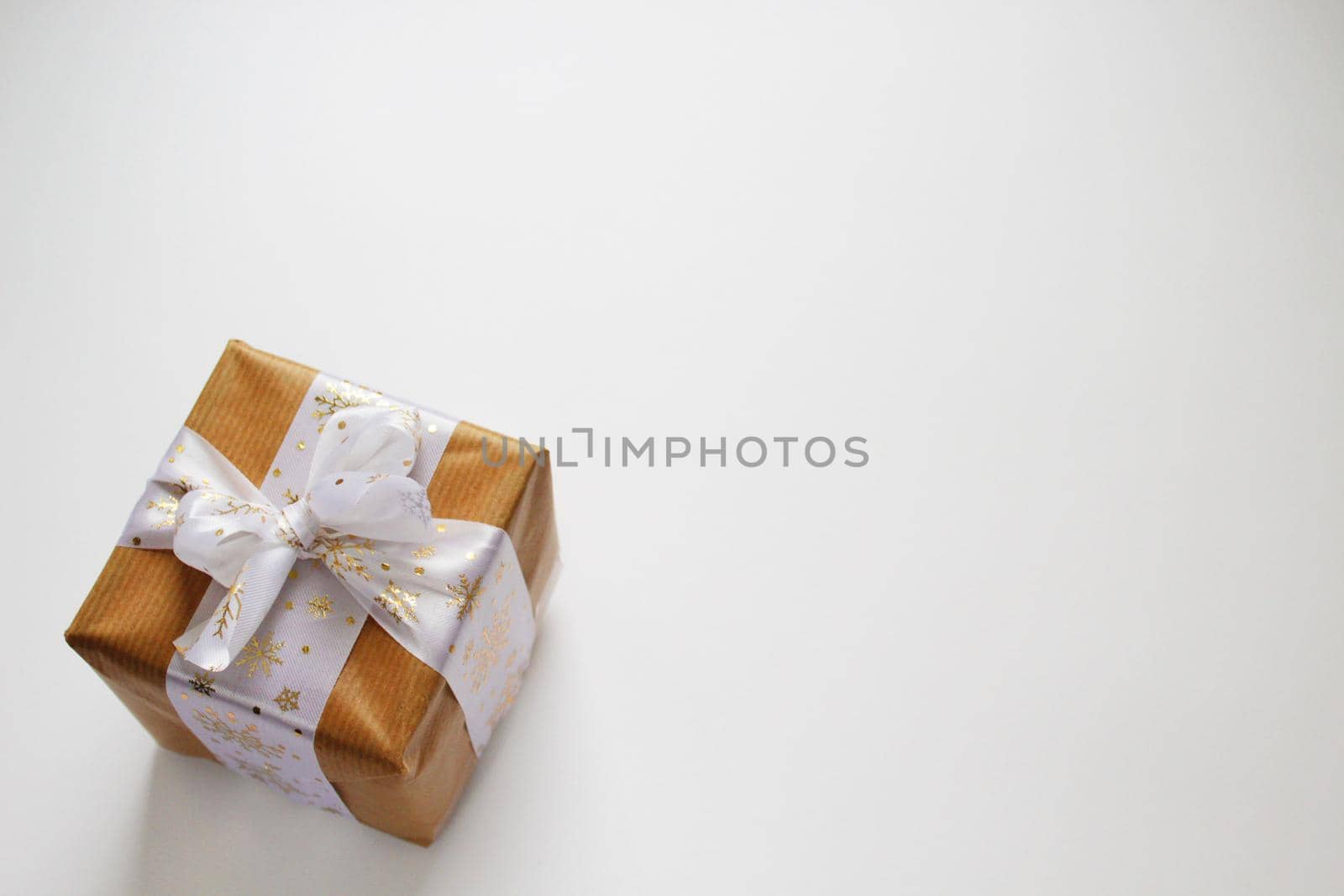 Vintage gift card for design. White paper texture background. Christmas gift in craft paper with white ribbon.