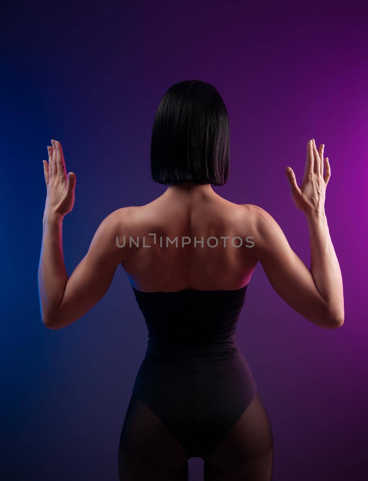 the strong muscular back of a brunette girl on a neon background