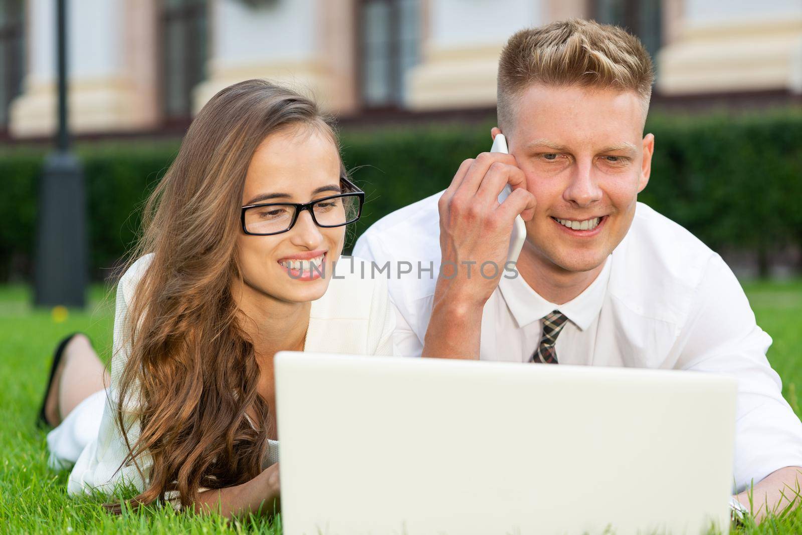 businessman and businesswoman with a laptop in a city park by adam121