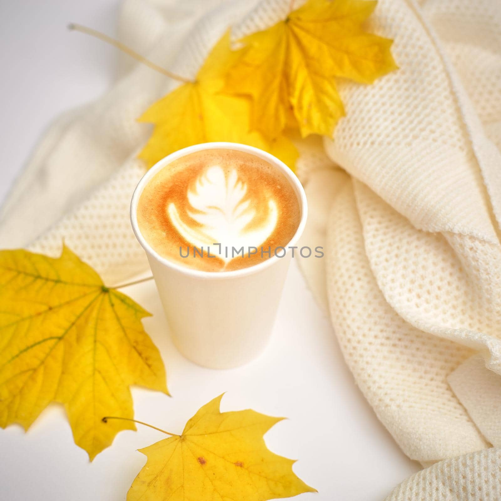 Paper coffee cup on autumn fall leaves with latte art. Street coffee, top view. selective focus