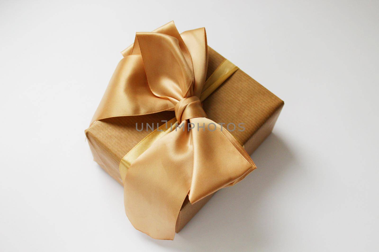 Gold gift box on a white background. Background, wrapping paper. White paper texture background. Gold ribbon.