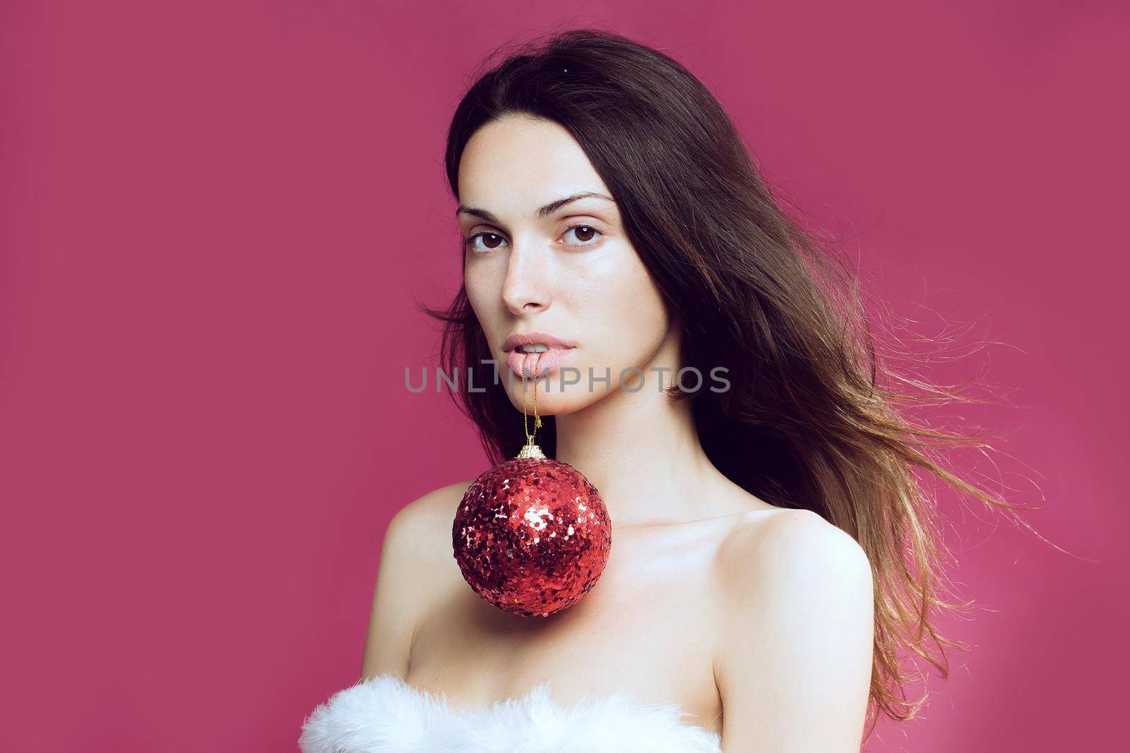 Sexy woman with christmas ball in studio on red pink background, copy space.