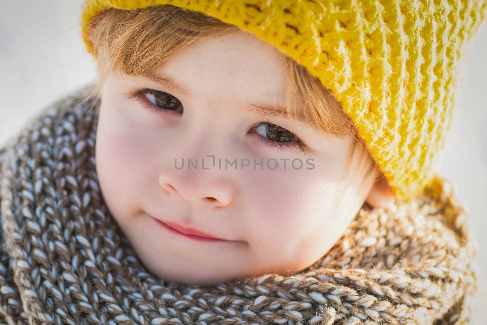 Close up face of cute boy kid in winter clothes walking under snow. by Tverdokhlib