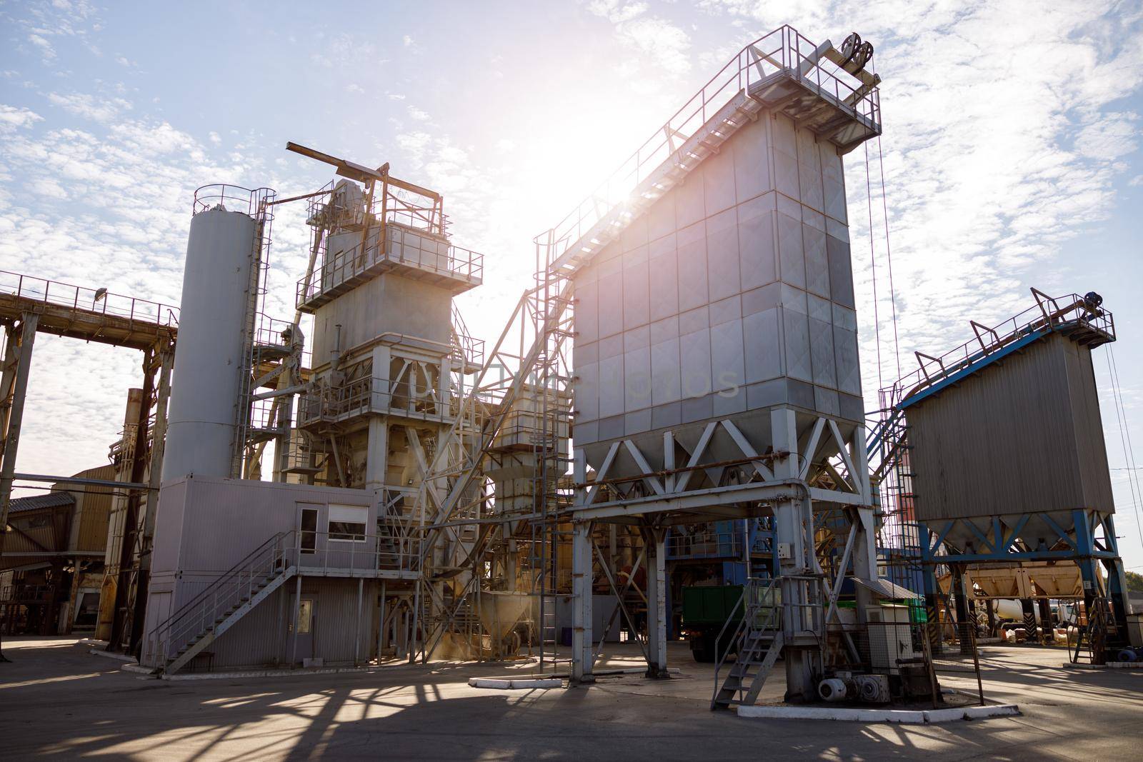 Manufacturing plant with industrial buildings, construction systems and ladders under cloudy sky