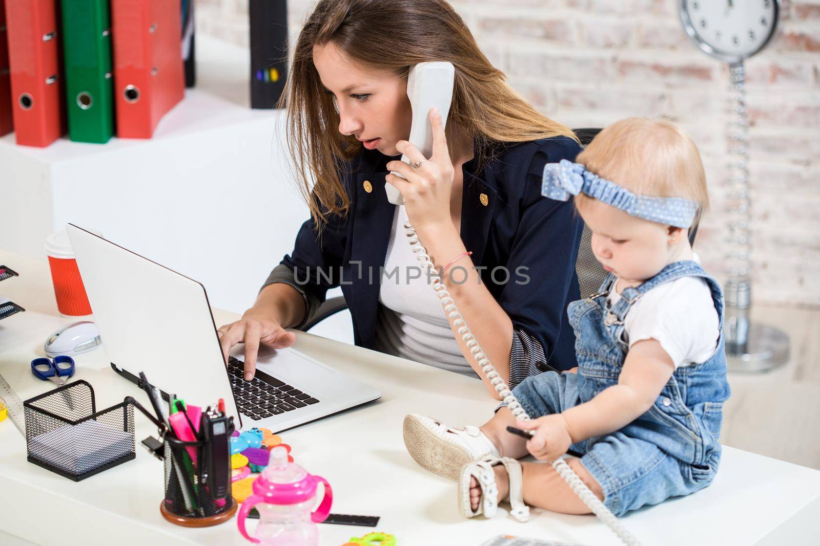 Businesswoman mother woman with a daughter working at the computer. At the workplace, together with a small child