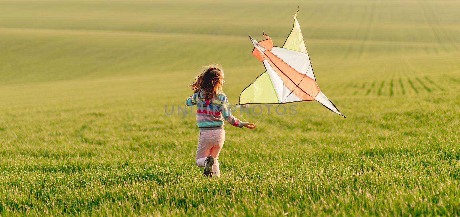 Little girl holding kite at sunset by tan4ikk1