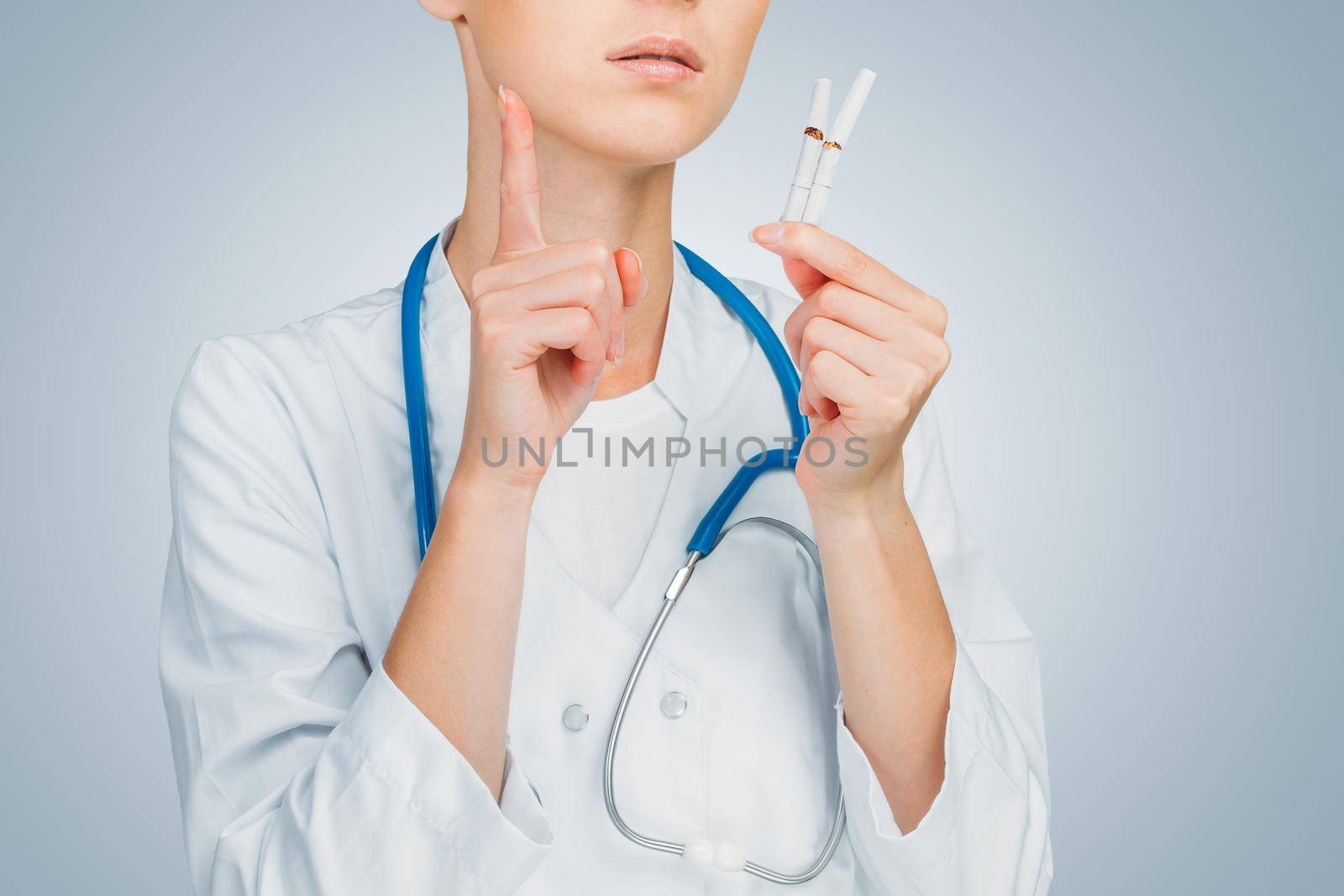Unrecognizable doctor holds broken cigarettes, smoking cessation