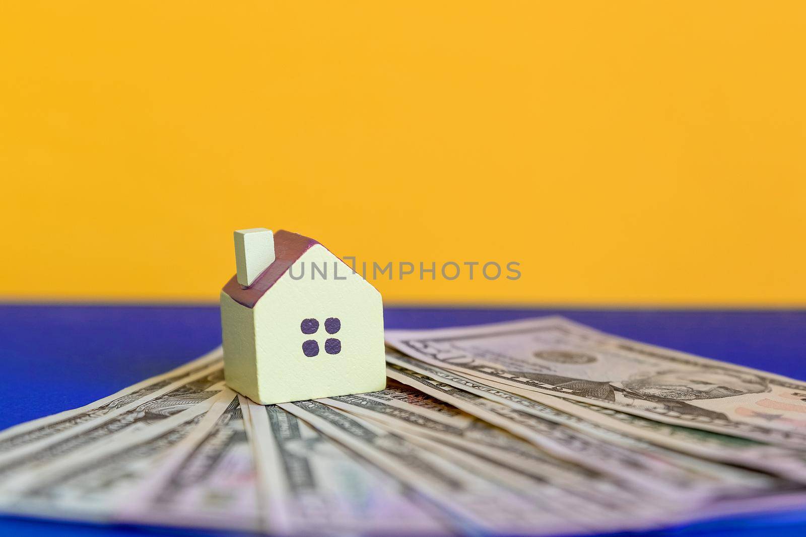 A small copy of the house and eco house made of grass stands on a bundle of dollars.