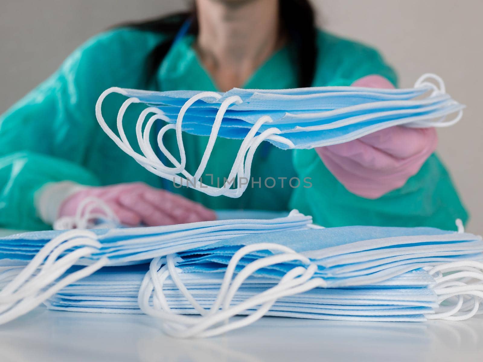 Close-up of a gloved woman counting blue masks at a table. by Utlanov