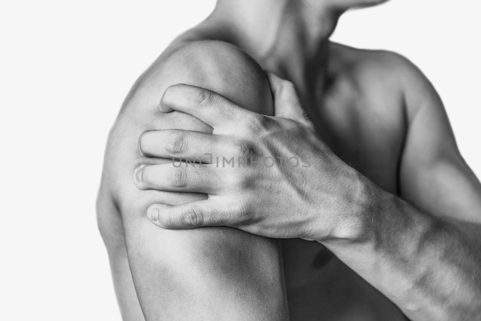 Unrecognizable man compresses his shoulder, pain in the shoulder, side view. Shoulder closeup. Monochrome image, isolated on a white background