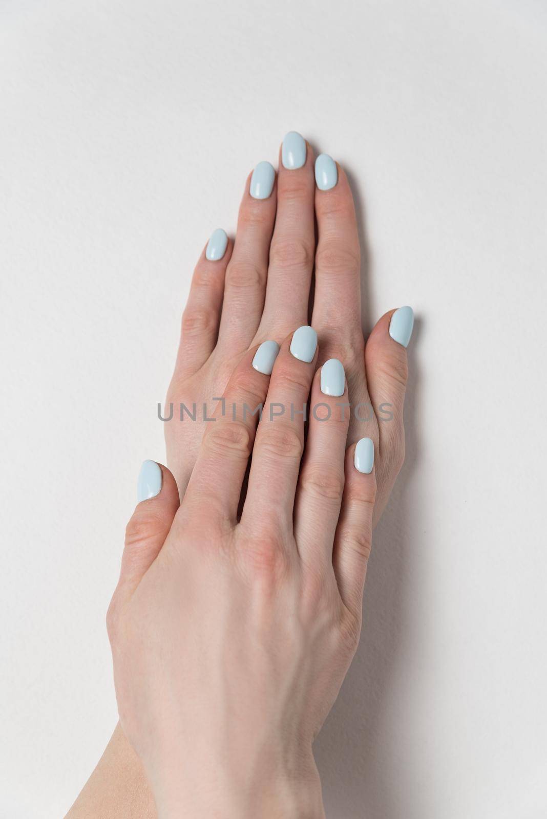 Gentle summer manicure, gel Polish. Female hands on white background. Verrical frame.