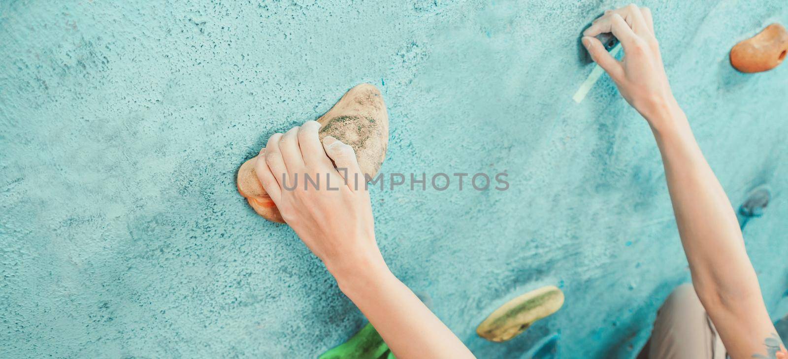Climber young woman starting bouldering track on artificial wall indoor, view of hands