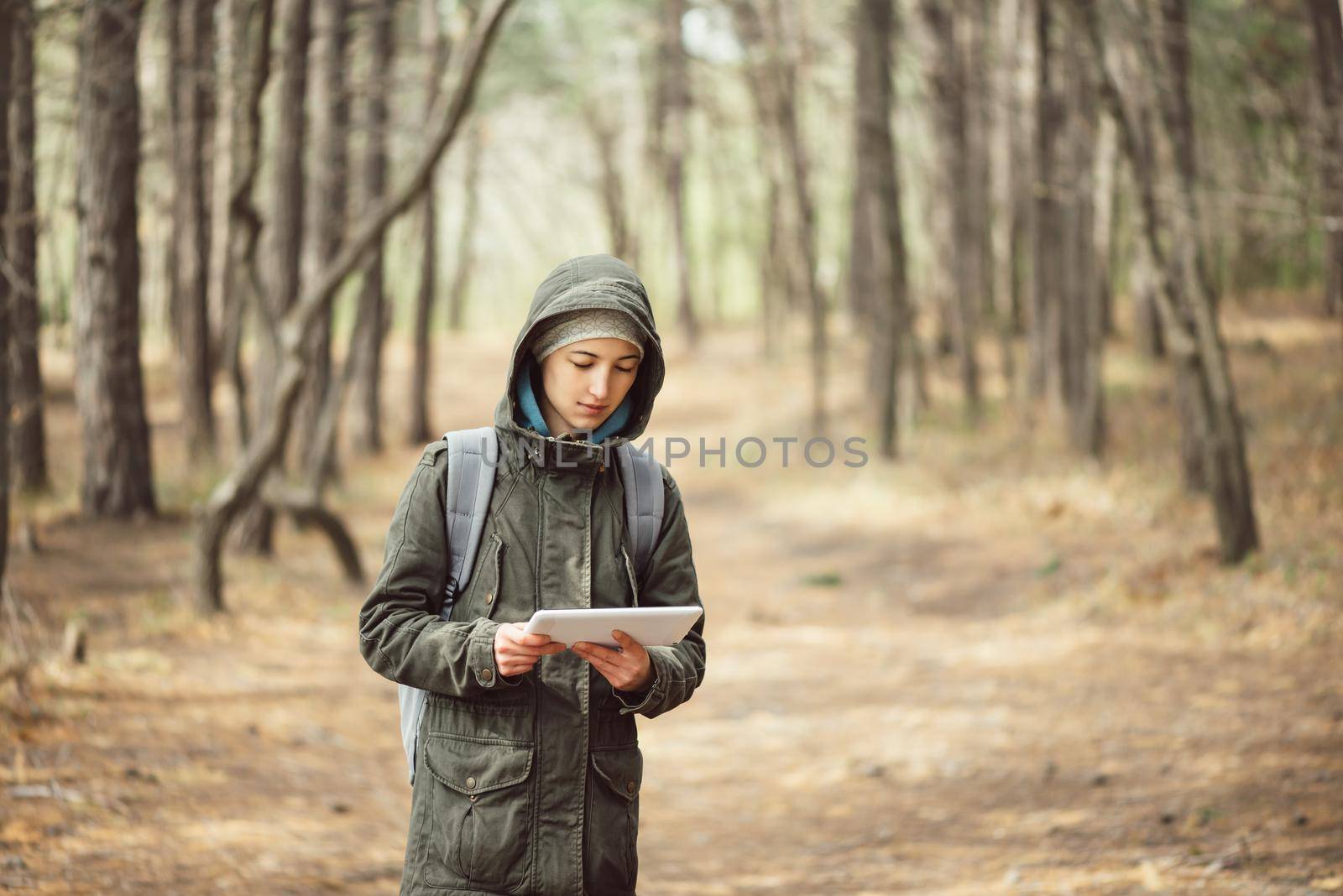 Hiker young woman walking with digital tablet in the forest. Concept of technology and travel