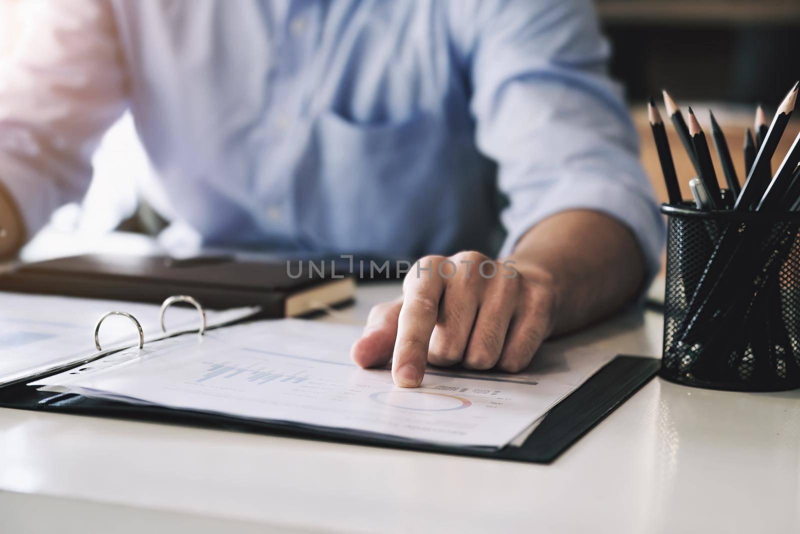 Examining the financial budget, a male auditor is pointing to a file to summarize the company's irregular financial budget