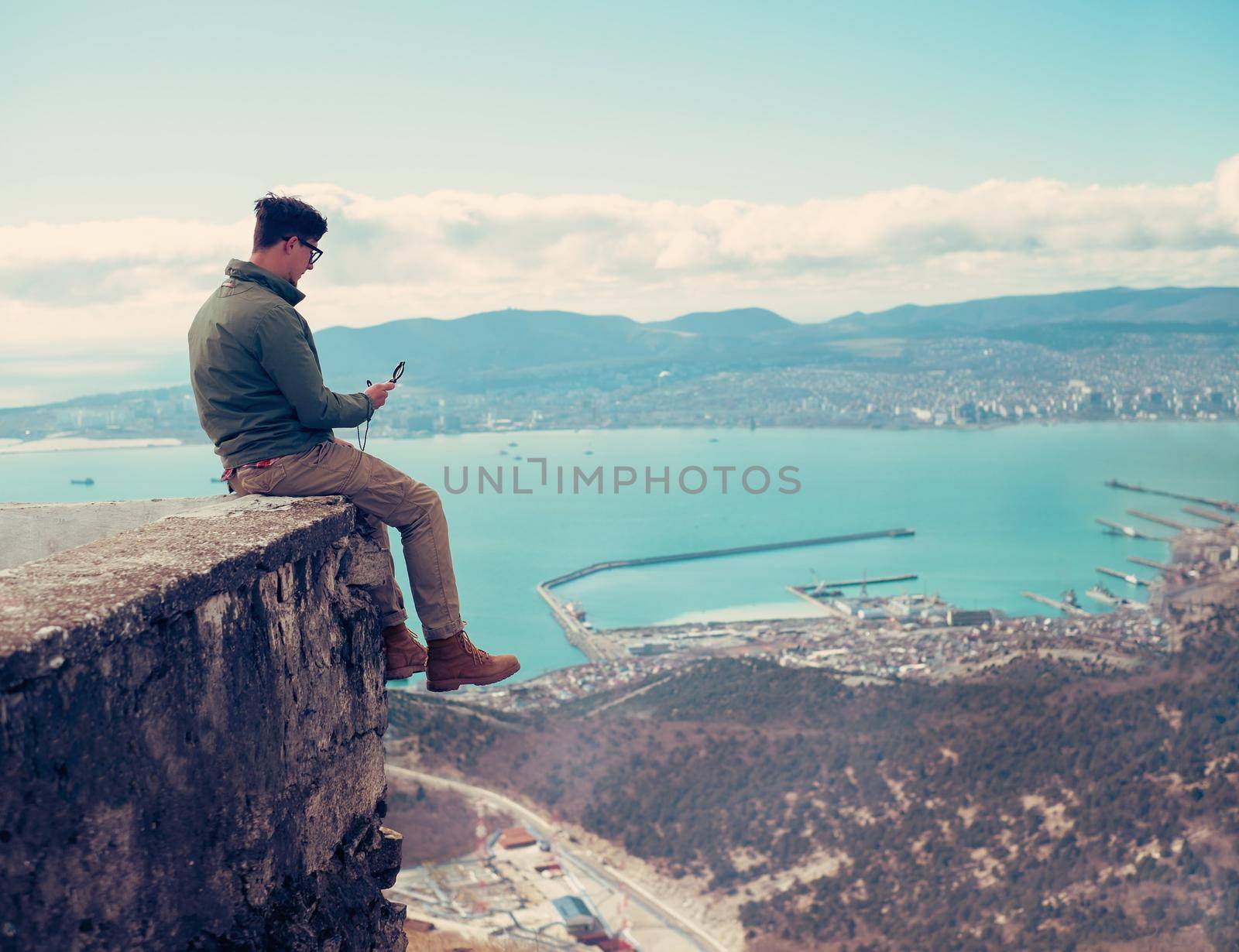 Traveler young man sitting with compass over the sea bay and searching direction