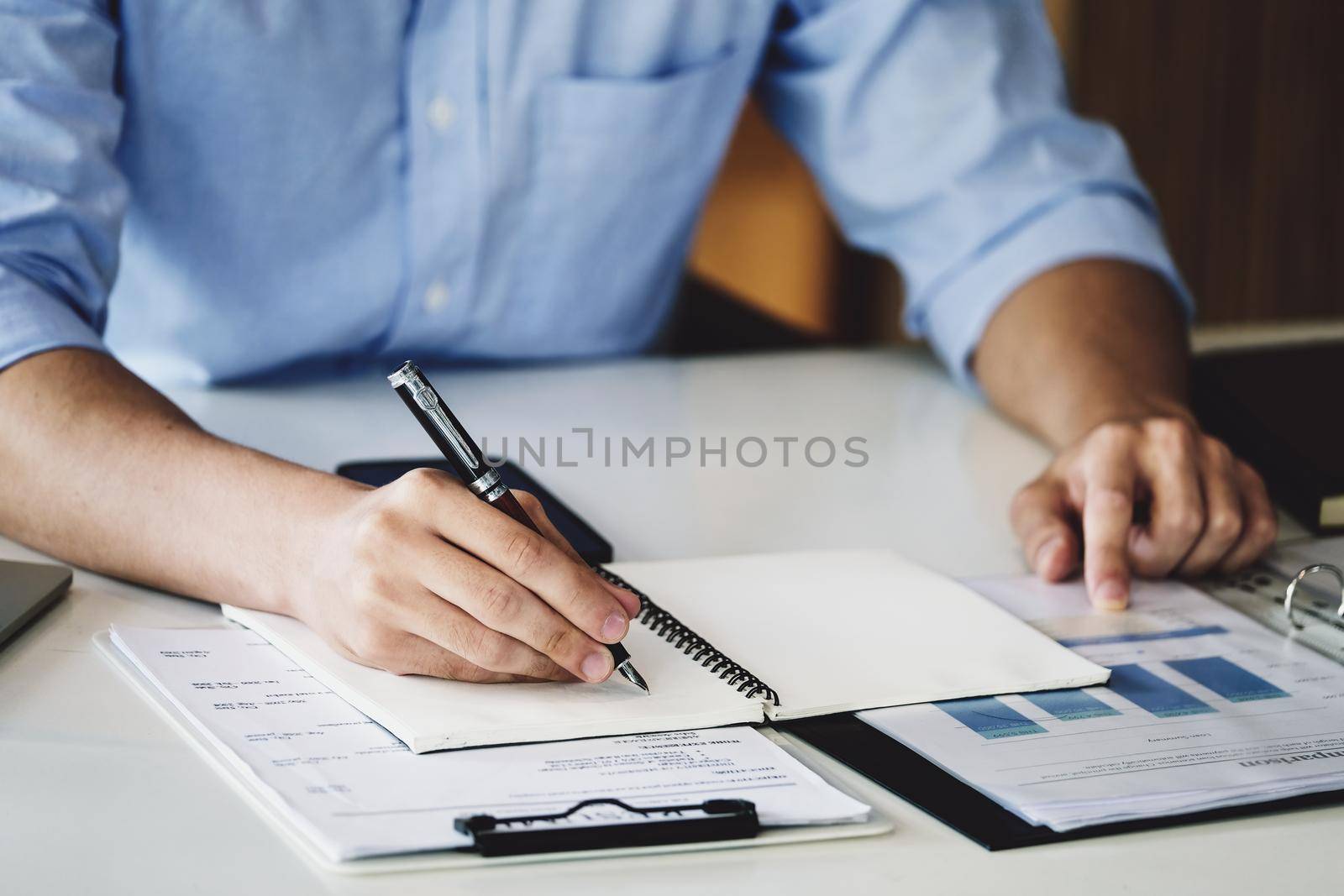 financial budget audit A male auditor is using a pen to write down budgets to trace the company's financial fraud. by Manastrong