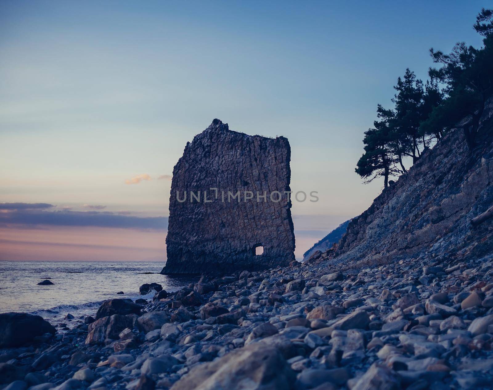 Rock Sail on pebble coast of Black sea in evening at sunset, Gelendzhik town, Russia