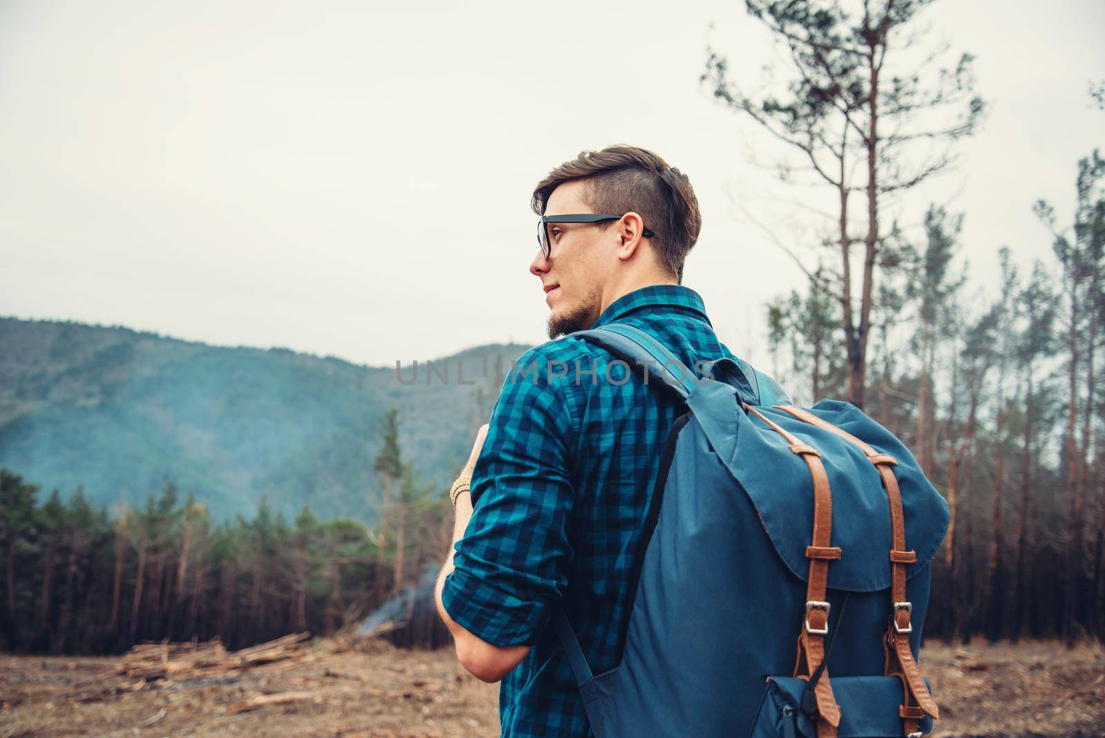 Handsome traveler young man with backpack walking in the forest