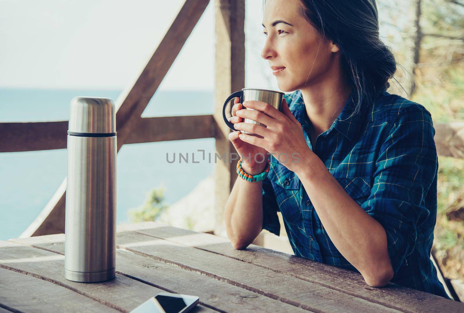 Young woman resting in wooden veranda in summer outdoor. Girl drinking tea in arbor