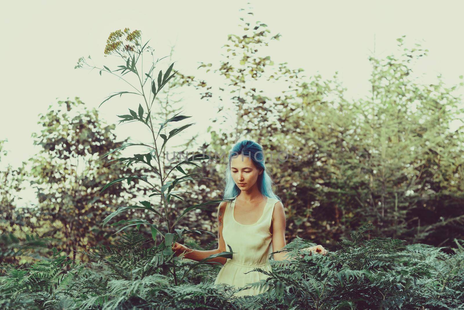 Beautiful girl with blue hair walking in fairy forest, girl standing near a big flower. Toning color