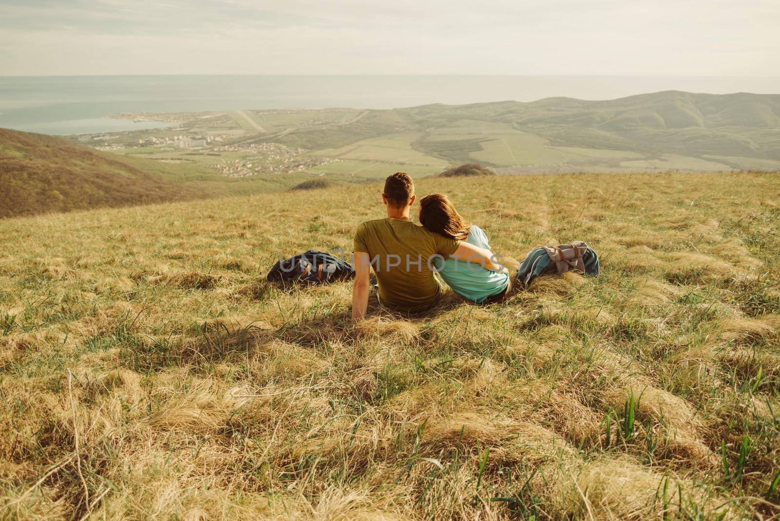 Young loving couple resting on meadow and enjoying view of nature in spring