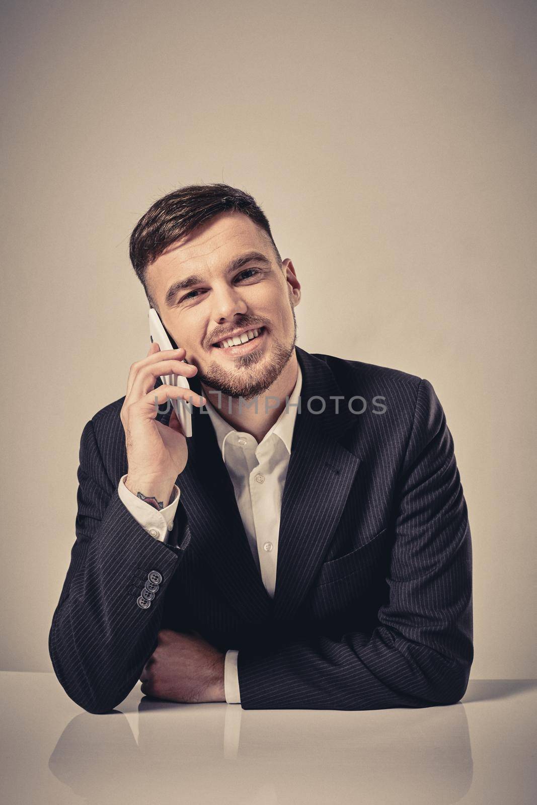 Handsome young man talking on the mobile phone while sitting at his working place in office. Emotions