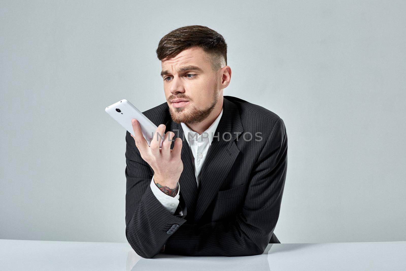 Handsome young man talking on the mobile phone while sitting at his working place in office. Emotions