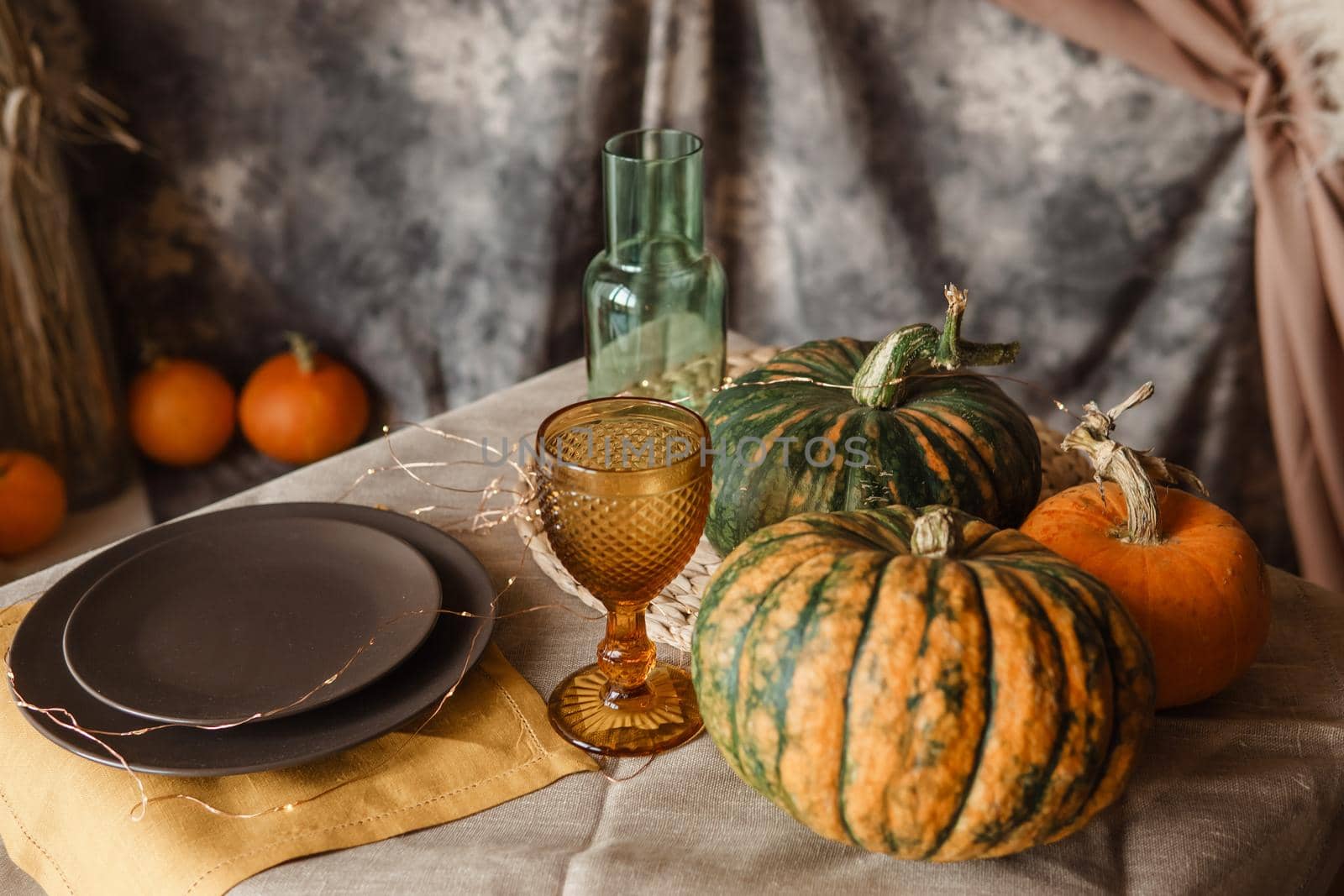 Autumn interior: a table covered with dishes, pumpkins, a relaxed composition of Japanese pampas grass. Interior in the photo Studio. Close - up of a decorated autumn table.