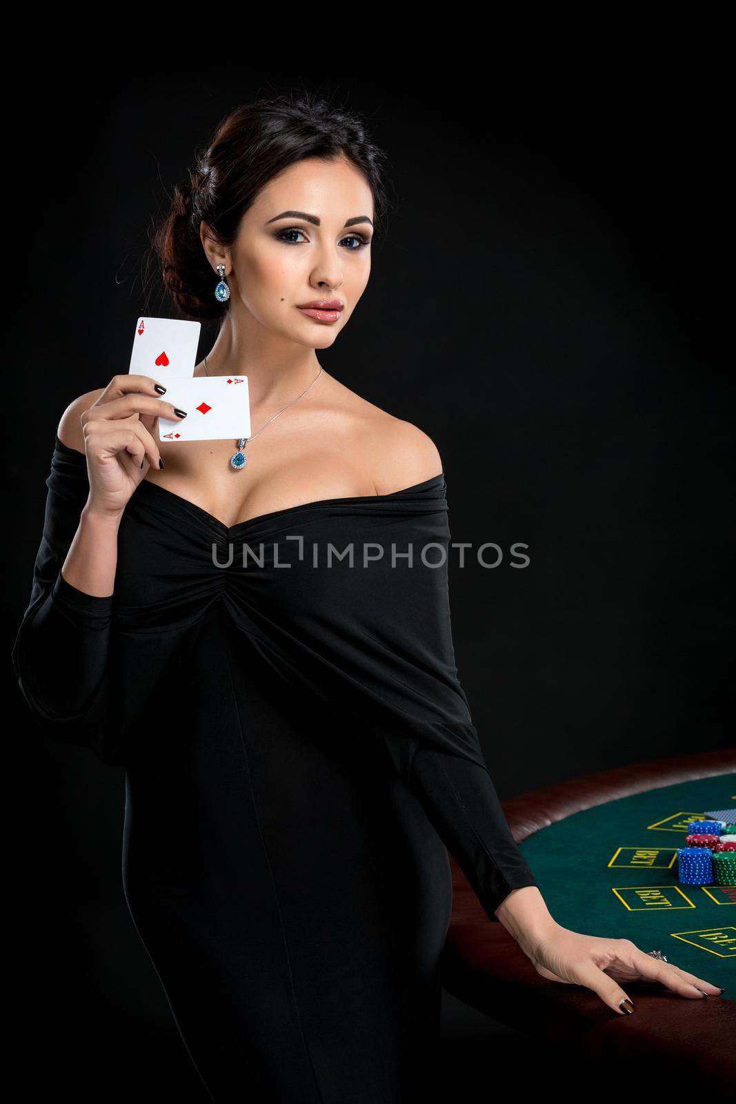 sexy woman with poker cards. Female player in a beautiful black dress. girl stands near the poker table and holds two aces