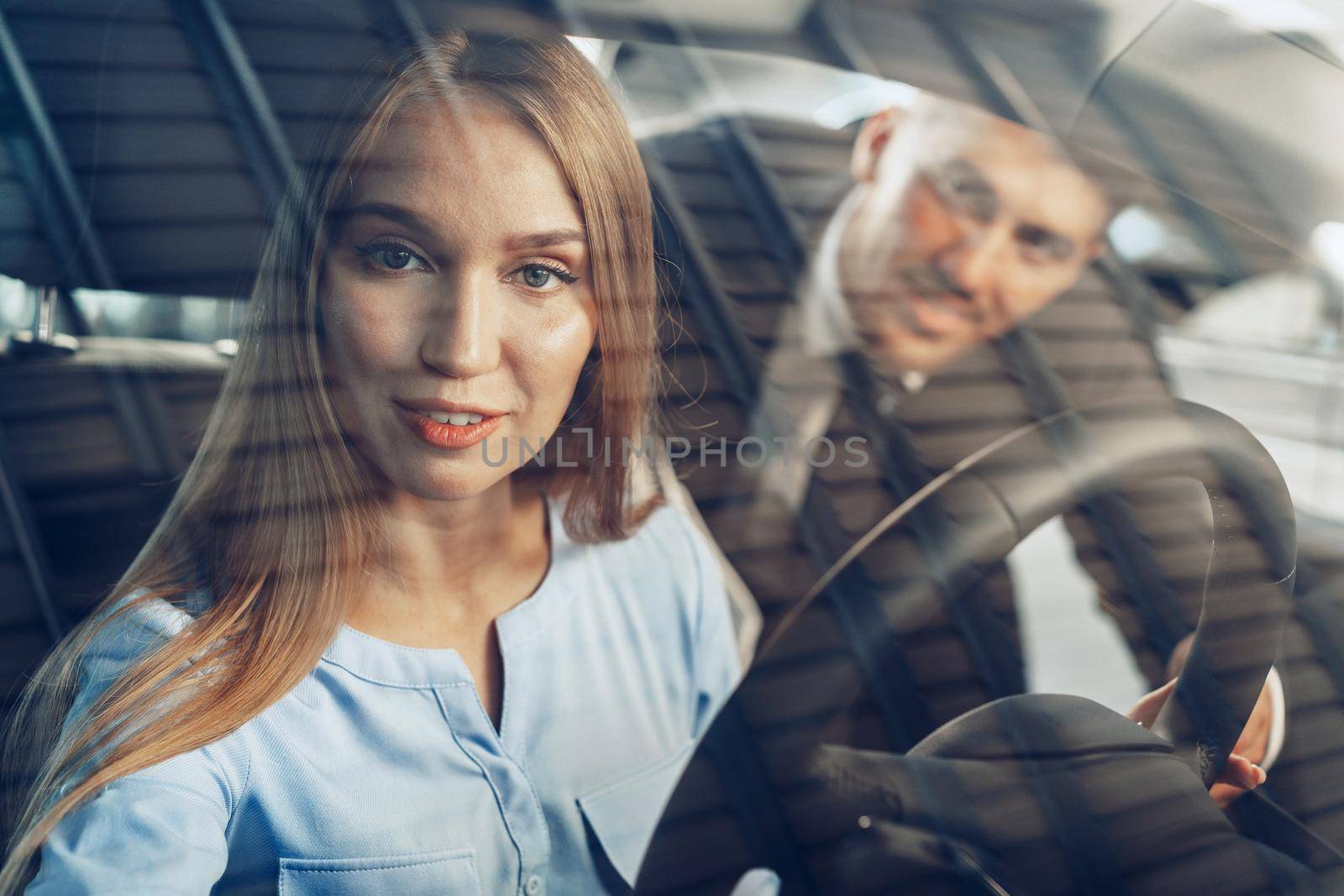 Attractive young woman sitting in new car in showroom close up