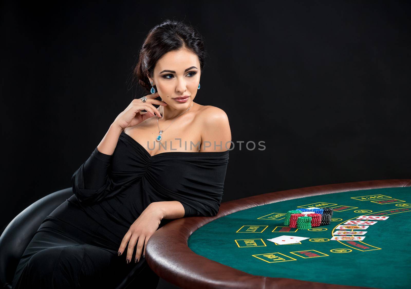 sexy woman with poker cards and chips. Female player in a beautiful black dress. girl sitting at the poker table