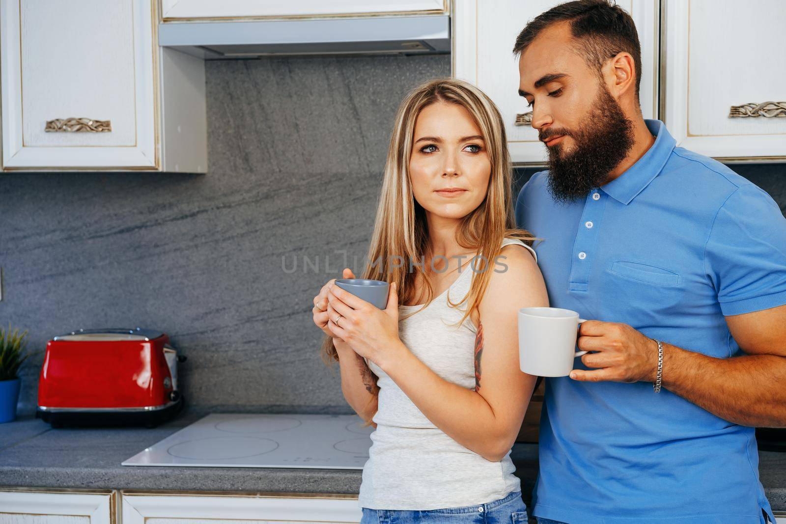 Young woman and man family relaxing with cups of tea at home in kitchen