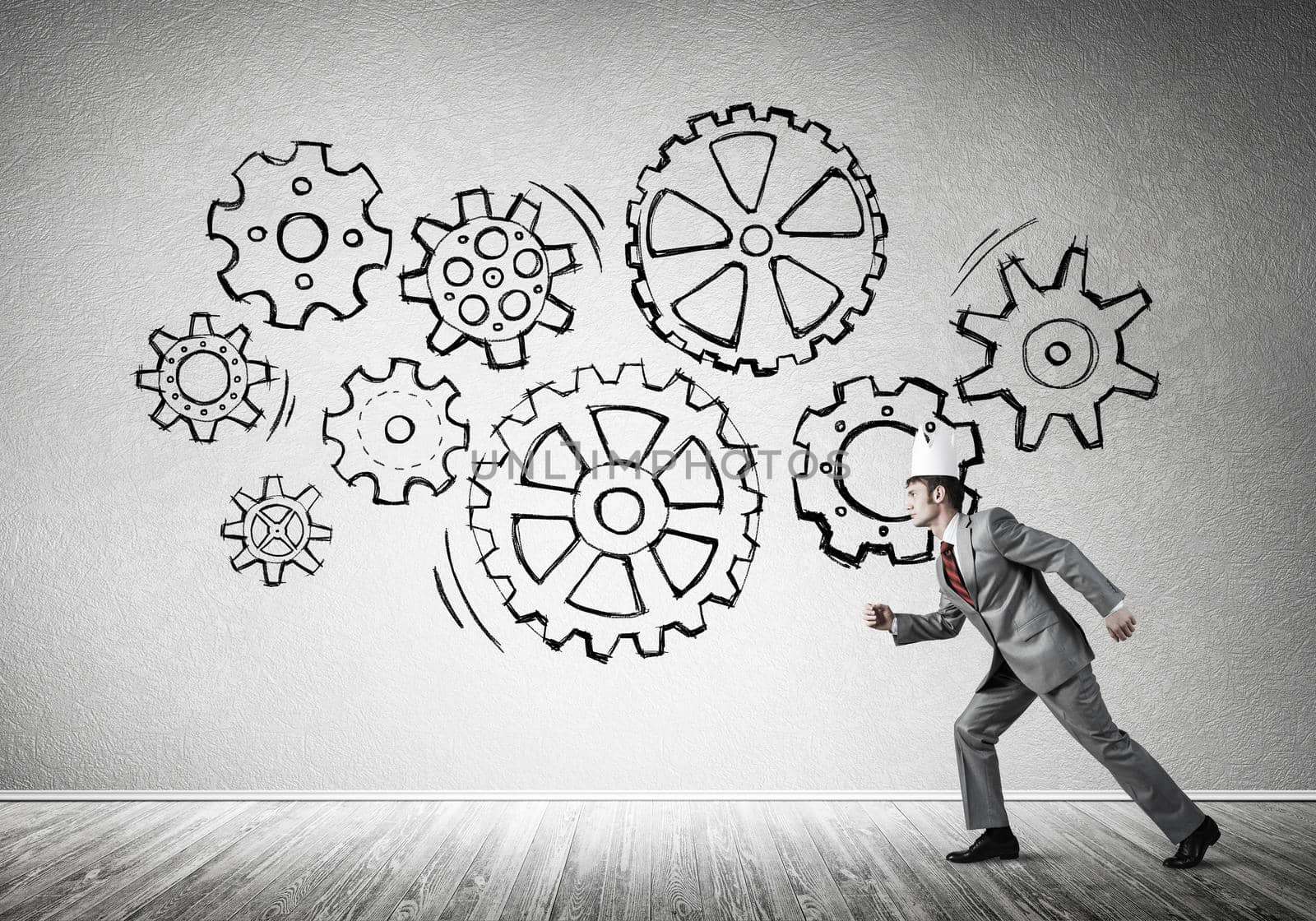 Young handsome businessman wearing white paper crown running and gear mechanism on wall