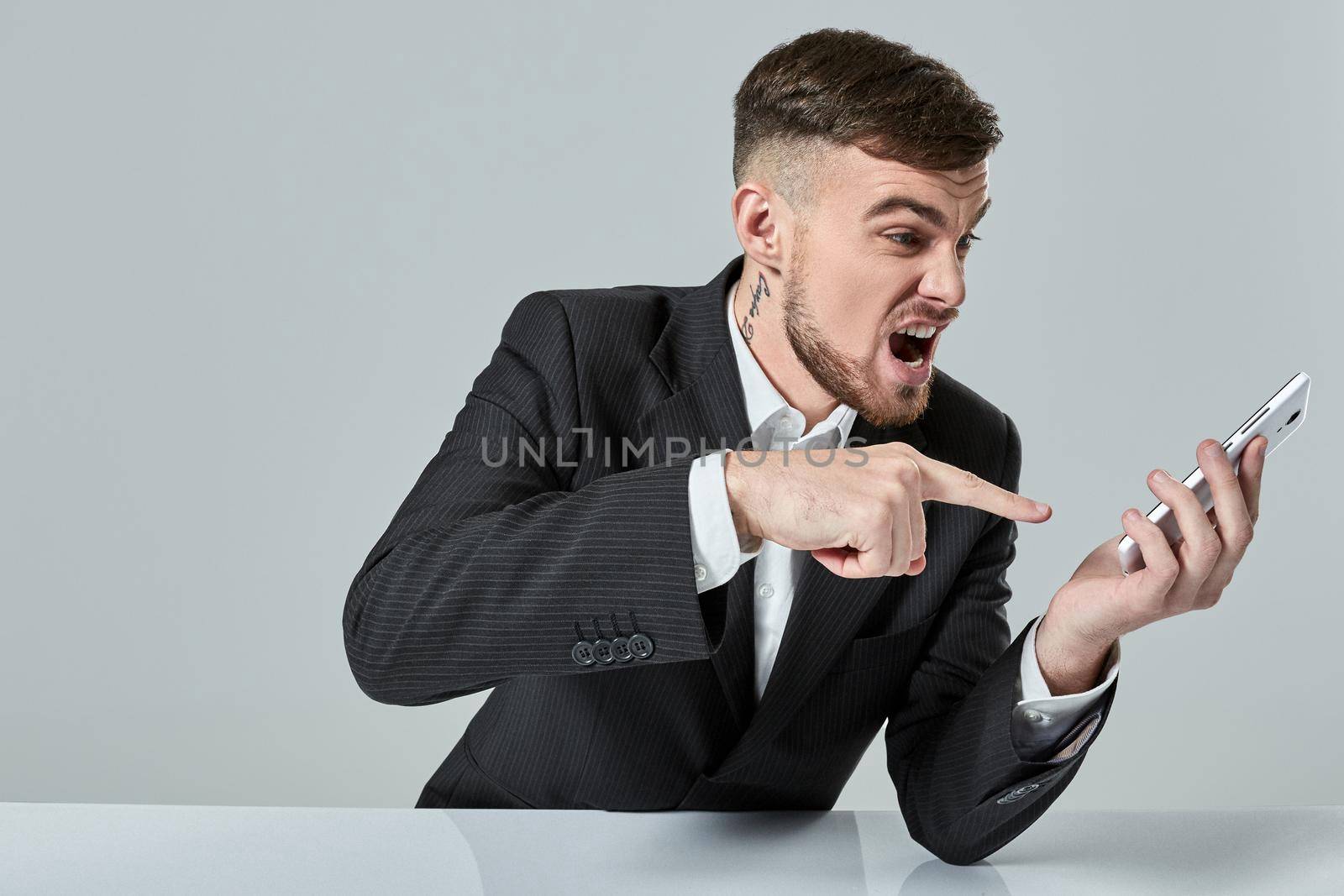 Handsome young man talking on the mobile phone while sitting at his working place in office. Emotions