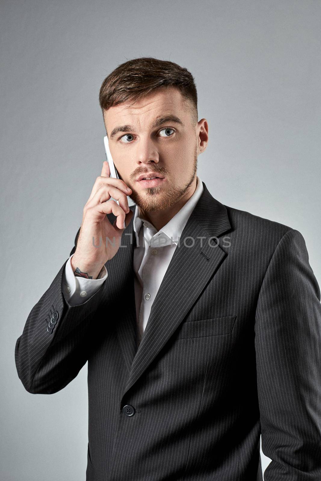 Portrait of a handsome businessman making phone call against grey background by nazarovsergey
