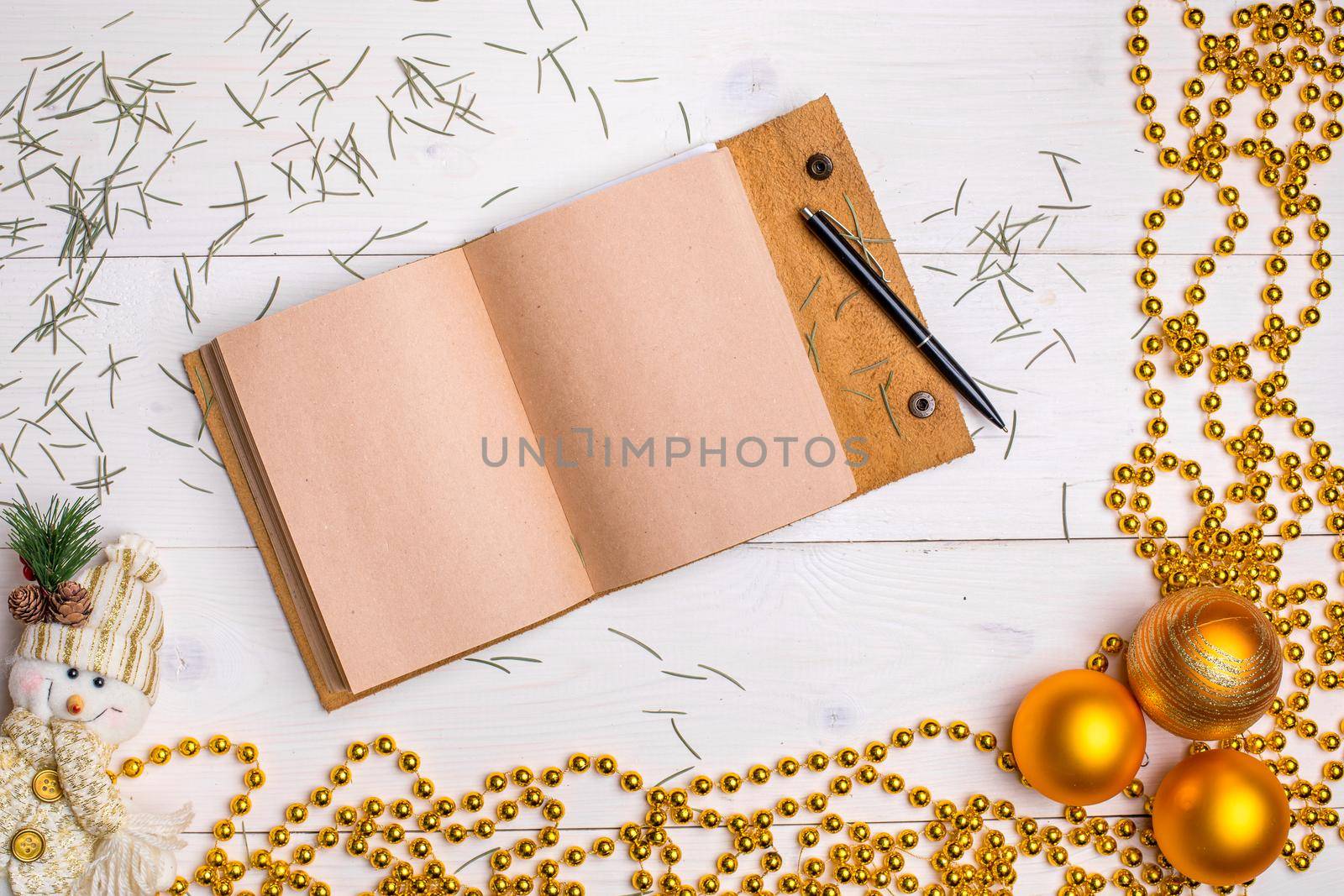 New Year and Christmas mokcup. notebook with Xmas lights on white wooden background, space for your text, copyspace Flat lay style.