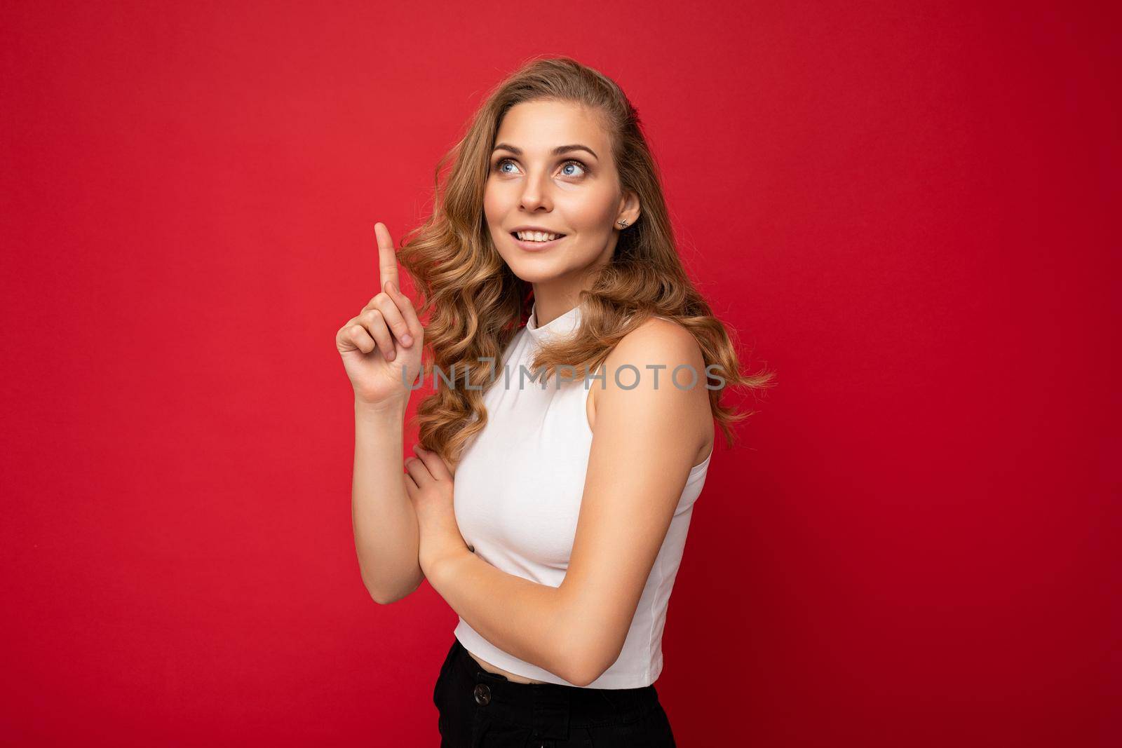 Photo of attractive positive young woman pointing fingers up at copyspace presenting ads promo with wow omg sincere emotions wearing good look outfit isolated over background with free space.