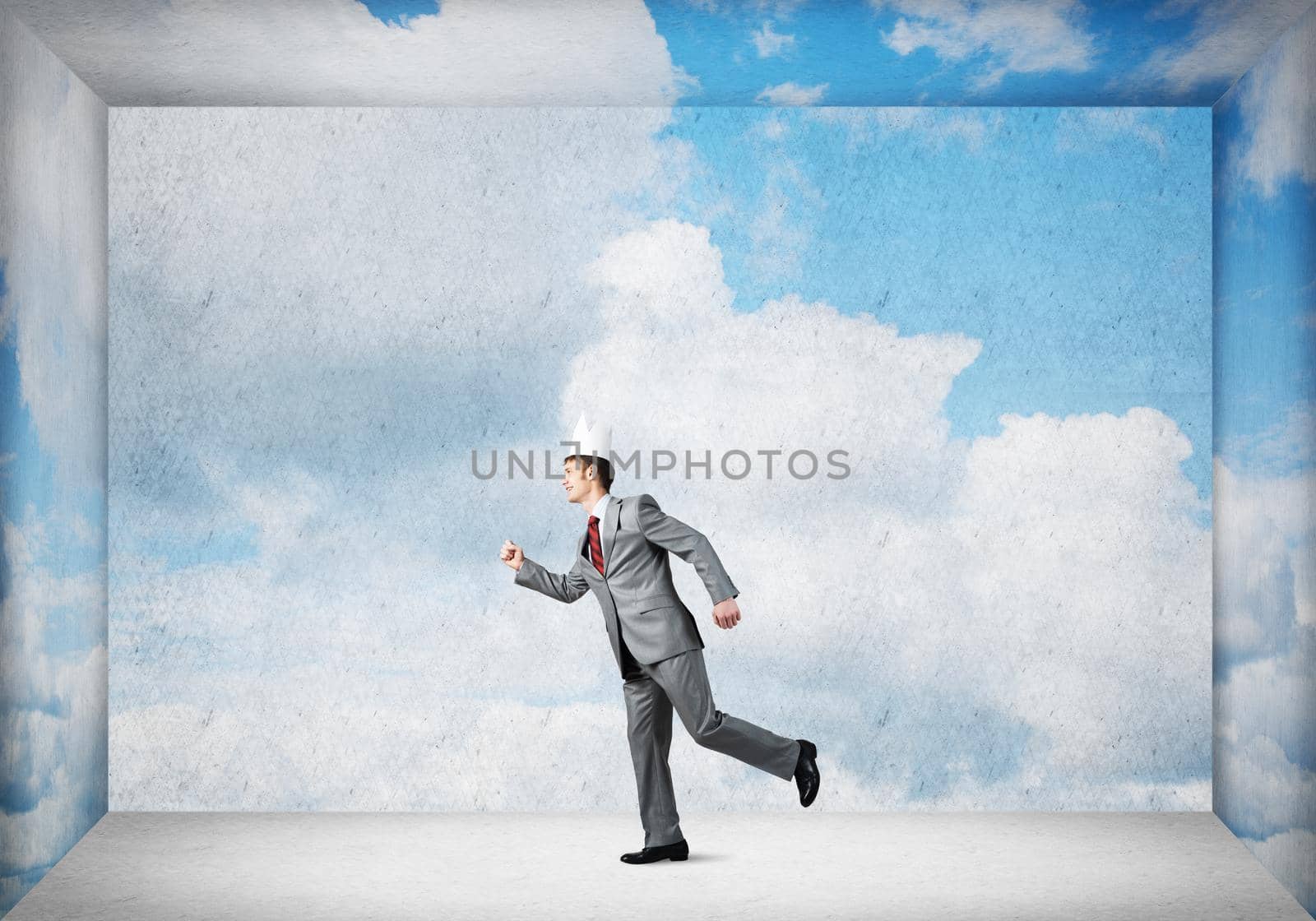 Young handsome businessman wearing white paper crown running in a hurry