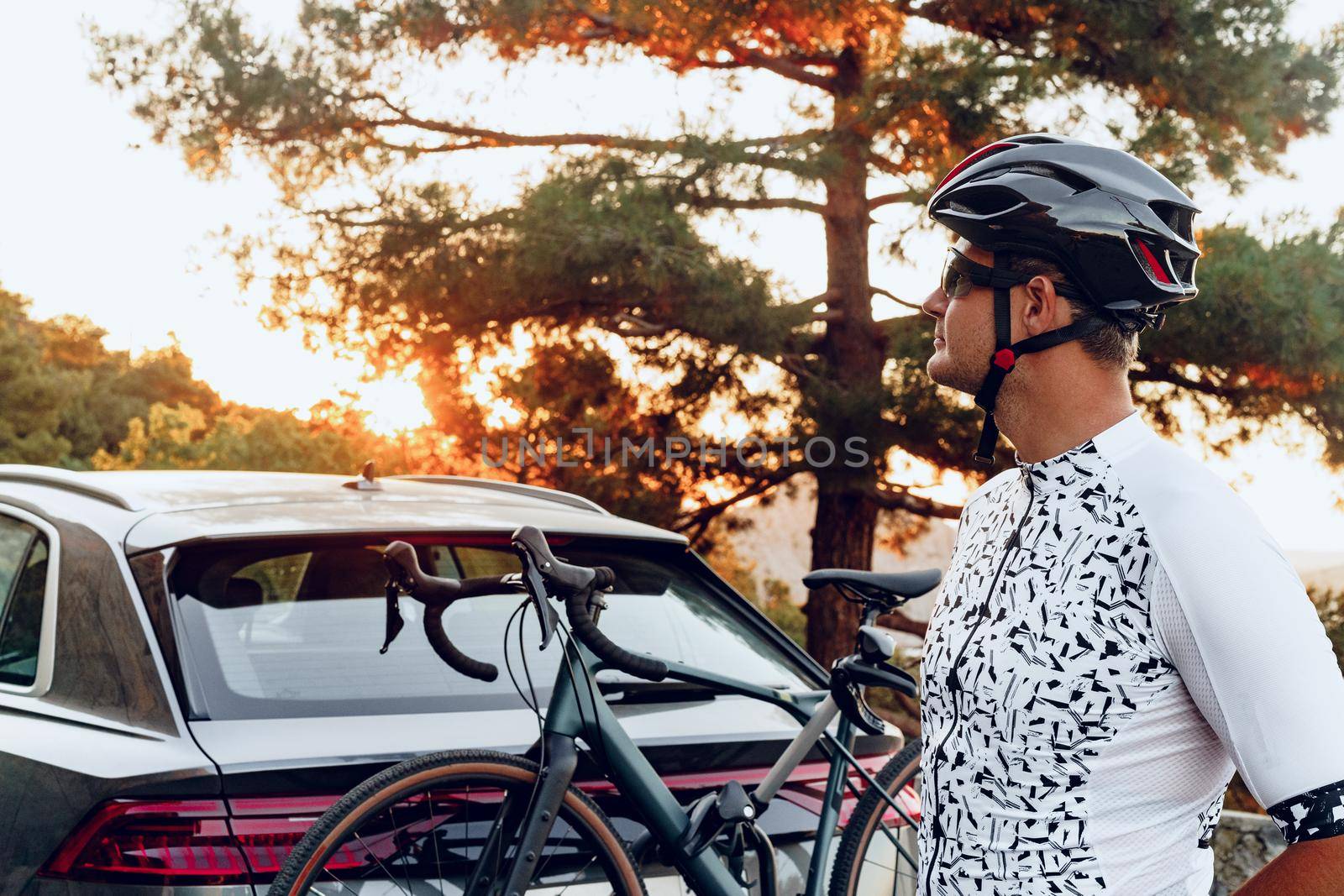 Male cyclist loading his bicycle on a rack of his crossover car after a ride